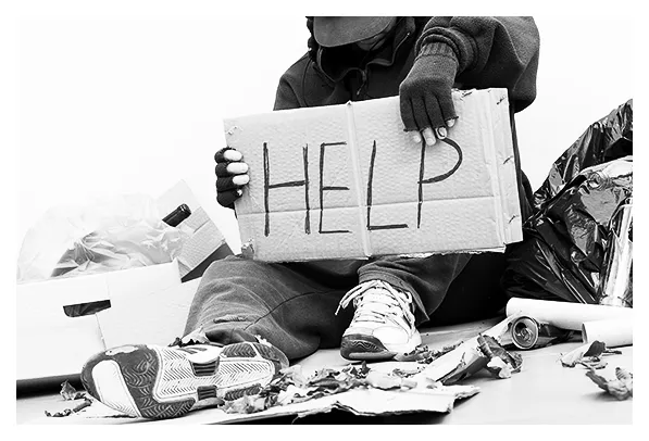 Homeless man holding a placard that says "HELP"